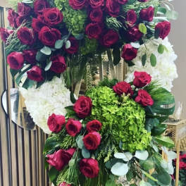 Large standing floral wreath of red roses, white hydrangeas, and green accents