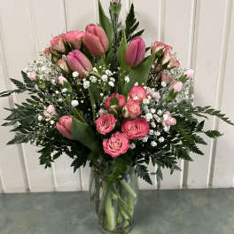 Pink tulips and roses arranged in a clear glass vase