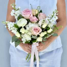 Handheld bouquet of pink and white roses with white blooms and ribbon