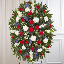 Standing funeral spray with red roses, white mums, and blue flowers