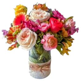Mixed bouquet of colorful roses and gerbera daisies in a glass vase