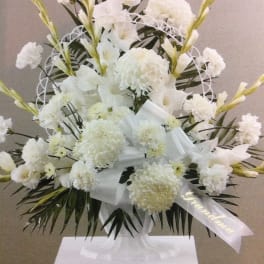 White floral standing arrangement with ribbon on a pedestal
