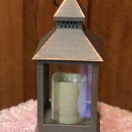 Metal lantern with a candle inside on a pink textured cloth