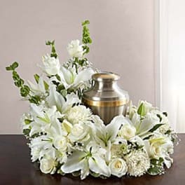 White floral funeral wreath around a brass urn