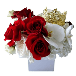 Red and white roses arranged in a white vase with a gold crown