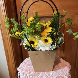 Sunflower and white hydrangea arrangement in a brown handled basket