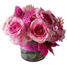 Pink roses and daisies in a glass vase with a pink butterfly decoration
