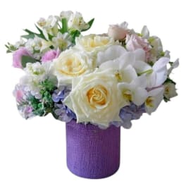 Bouquet of white and pastel flowers in a purple wrapped vase