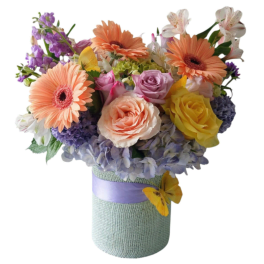 Mixed bouquet in a wrapped vase with peach gerberas, roses, and purple blooms