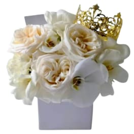 White roses and orchids in a lavender box with a gold crown topper