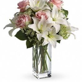 Pink roses and white lilies arranged in a clear glass vase