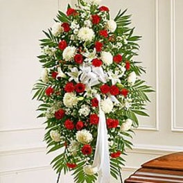 Tall standing spray of red and white flowers with a white ribbon on an easel