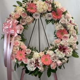 Large pink and white floral wreath on a stand with ribbon bow