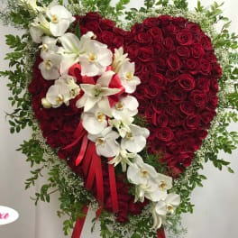 Heart-shaped red rose arrangement with white orchids and a red ribbon