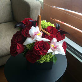 Bouquet of red roses with white orchids in a black box