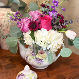 Bouquet of pink and white flowers in a floral teapot vase