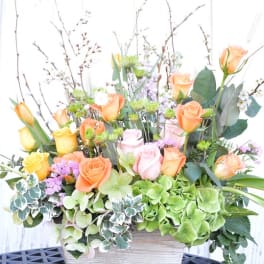Mixed bouquet of roses, tulips, and hydrangeas in a rectangular container