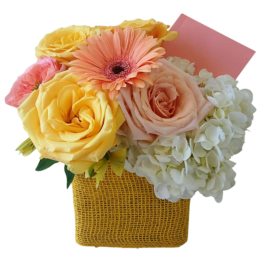 Bouquet of yellow and peach flowers in a woven basket with a pink card
