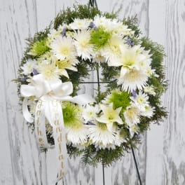 White floral wreath with a ribbon on a stand