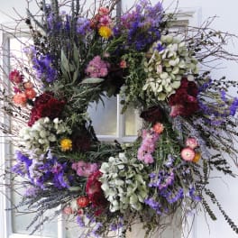 Large floral wreath with purple, pink, and white blooms on a window