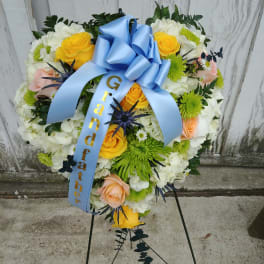 Heart-shaped floral wreath with a blue ribbon and stand