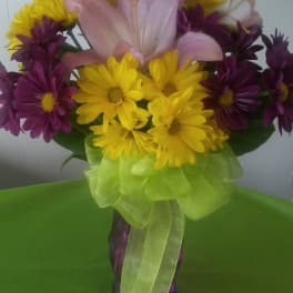 Bouquet of pink lilies and yellow and purple daisies in a vase