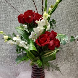 Red roses and white orchids in a tall red glass vase
