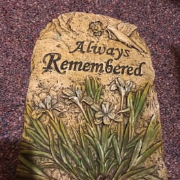 Decorative stone plaque with the words Always Remembered and carved flowers