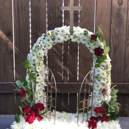 White floral funeral wreath with red roses and a cross topper