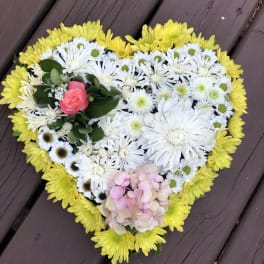 Heart-shaped floral arrangement with yellow, white, pink, and green blooms