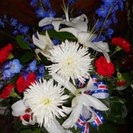 White lilies and chrysanthemums with blue and red flowers in a white vase