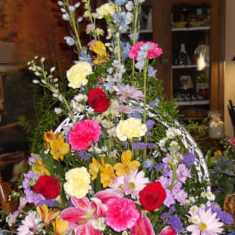 Tall mixed flower arrangement in a white container with pink lilies and red roses
