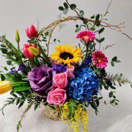 Colorful mixed bouquet with tulips, roses, sunflower, and hydrangea in a basket
