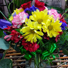 Mixed bouquet with yellow daisies, red roses, and pink carnations in a glass vase