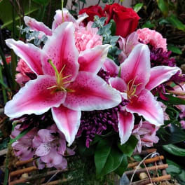 Bouquet of pink lilies and red roses in a glass vase