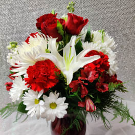 Red roses, white lilies, and daisies in a burgundy vase