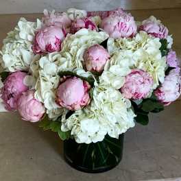 Pink peonies and white hydrangeas in a dark glass vase