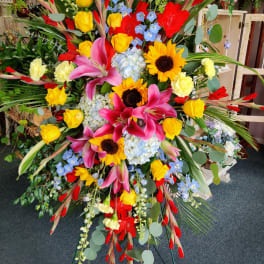 Large standing floral spray with sunflowers, pink lilies, and yellow roses