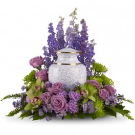 Purple floral arrangement around a white urn vase