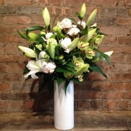 White lilies and green orchids in a tall white vase