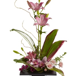 Tall floral arrangement with pink lilies and pale roses in a black vase