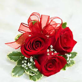 Three red roses with a red ribbon bow and small white filler flowers
