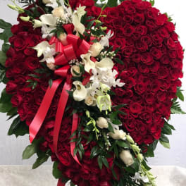 Heart-shaped red rose arrangement with white flowers and a red ribbon
