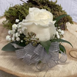 White rose arrangement with baby's breath and silver ribbon on a wood slice
