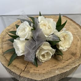 White rose bouquet with silver ribbon on a wood slice