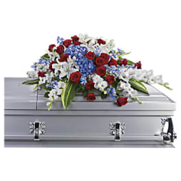 Red, white, and blue floral spray on a silver casket