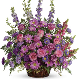 Pink and purple mixed flower arrangement in a wicker basket
