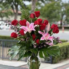 Red roses and pink lilies arranged in a clear glass vase