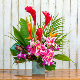 Tropical flower arrangement with pink lilies and red ginger in a square vase