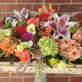 Large mixed floral arrangement with lilies, roses, and carnations in warm colors